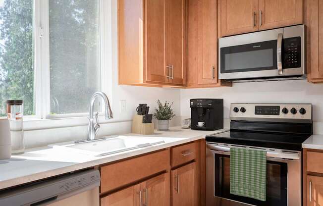 A kitchen with wooden cabinets and a black microwave above the stove.