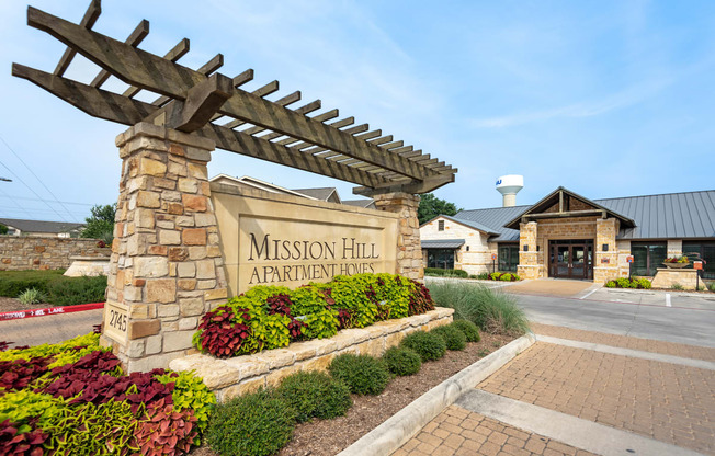 the entrance to mission hill apartments with a stone welcome sign