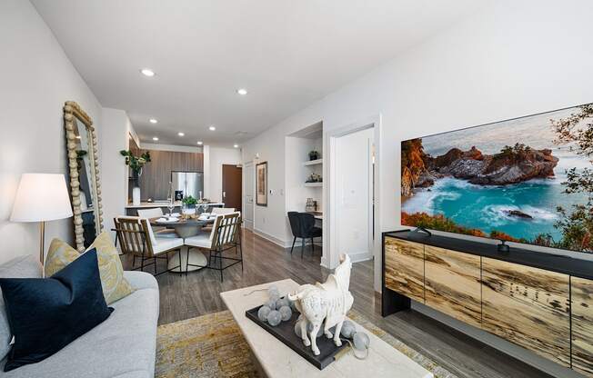 Bright living room with contemporary furnishings, wall-mounted TV, and open dining layout