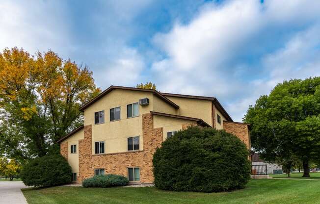 The view of an apartment building with green grass and trees. Fargo, ND Huntington Apartments.