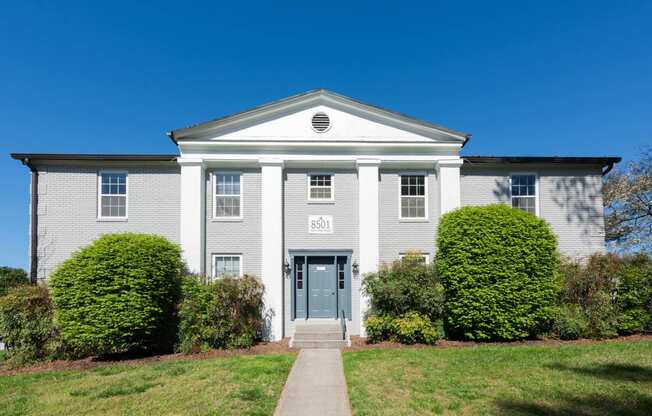 the front of a white house with a blue door