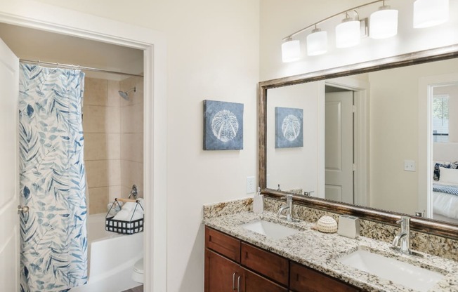 A bathroom with a patterned shower curtain and a large mirror.