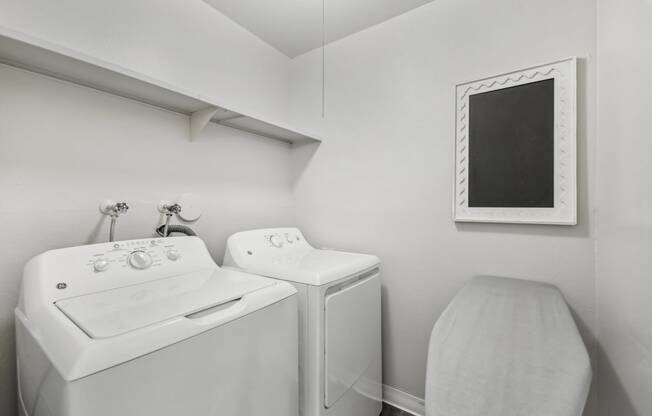 a white washer and dryer in a white laundry room with a white sink