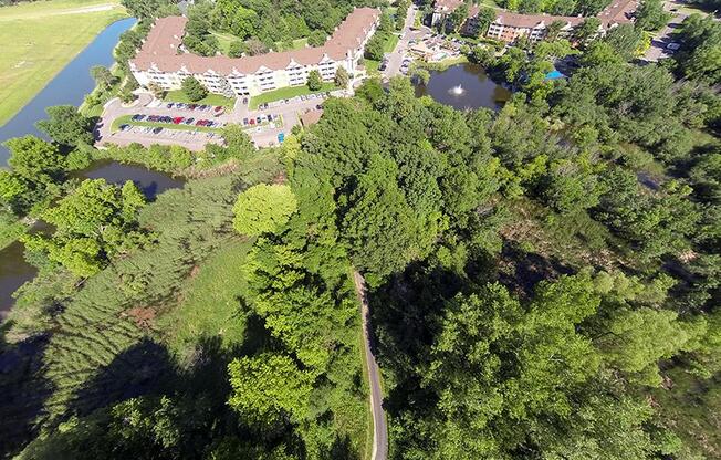 High altitutde view of property, showing buildings, trees, and a bike trail