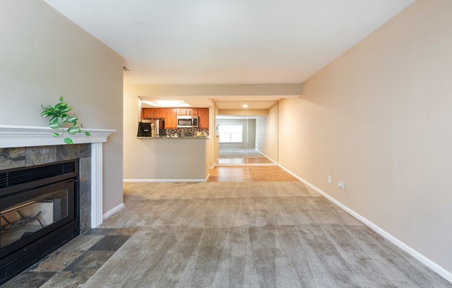 a living room with a fireplace and a hallway with a kitchen