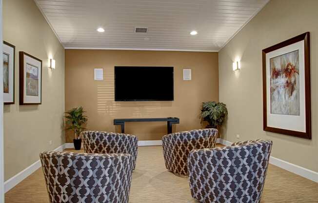 a room with a couch and chairs and a flat screen tv on the wall