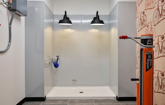 A bathroom with a shower and a bicycle patterned wallpaper.