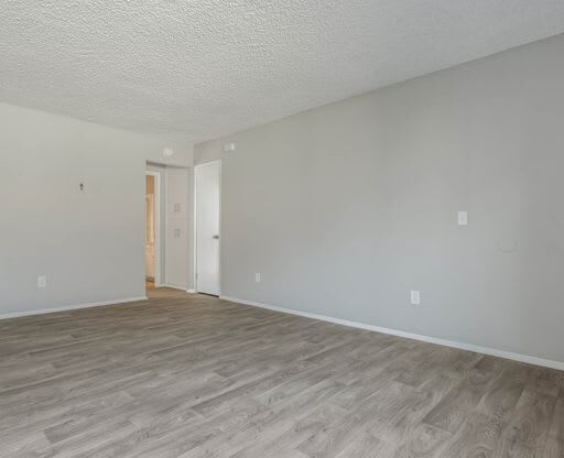 an empty living room with a wood floor at The Arches Apartments, El Cajon, CA