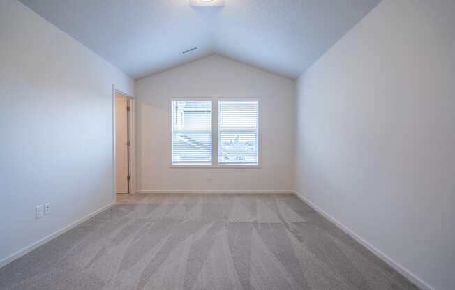 an empty bedroom with a window and a door