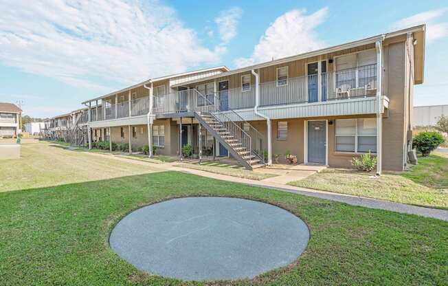A concrete circle is in the middle of a grassy area in front of apartment buildings  at The Creole Apartments in Shreveport, LA