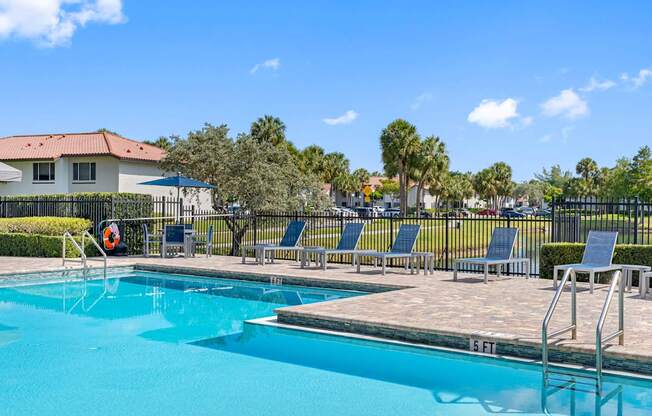 A swimming pool with a ladder and chairs around it.