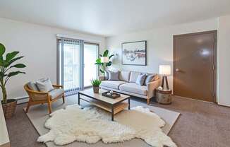 A living room with a white rug and a wooden coffee table.