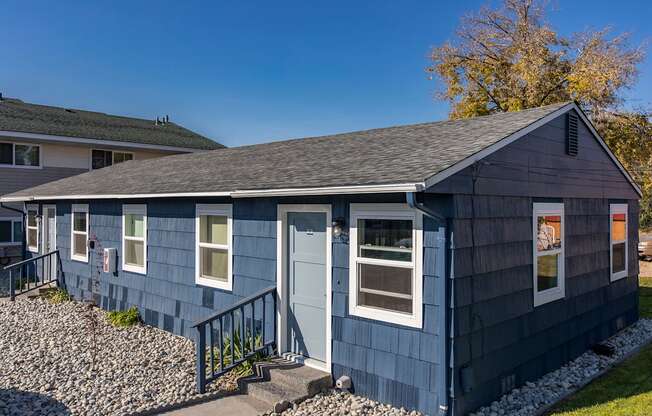 Paved path to the exterior of homes with many windows surrounded by decorative rocks, grass, and landscaping.at The Lakes Apartments, Moses Lake Washington