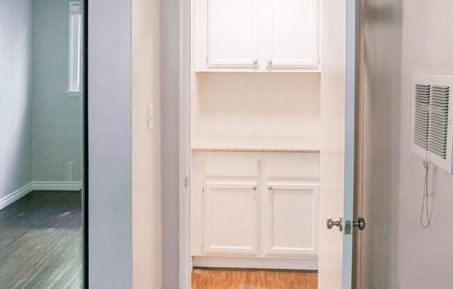 an empty room with white cabinets and a hallway to a closet