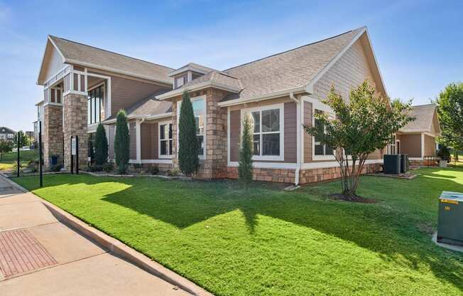 A house with a brown roof and a green lawn in front.