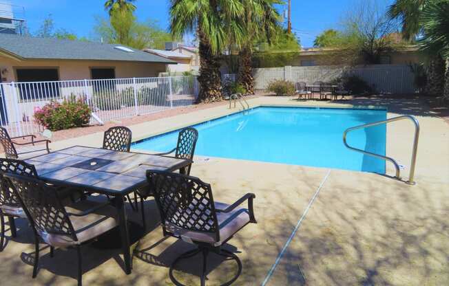 a patio with a table and chairs next to a swimming pool