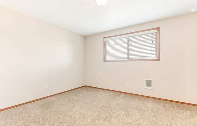 a bedroom with white walls and a window