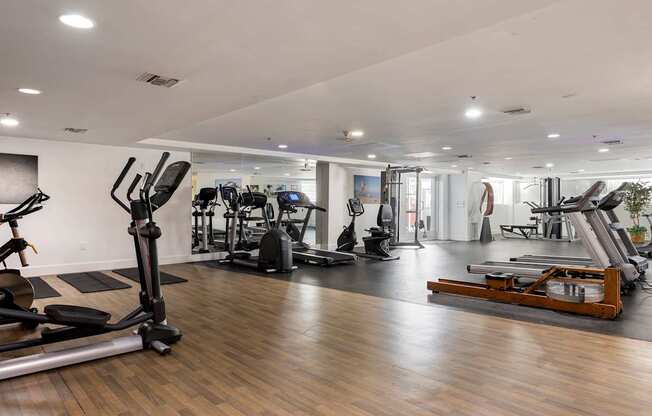 A gym with a variety of equipment including treadmills, weights, and exercise machines.