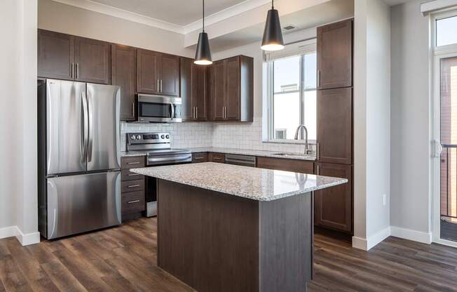 A kitchen with a refrigerator, microwave, oven, and sink.