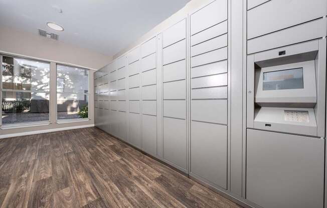 A row of white lockers are lined up in a room with wood flooring.