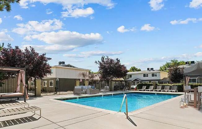 A swimming pool surrounded by a concrete patio and a few trees.