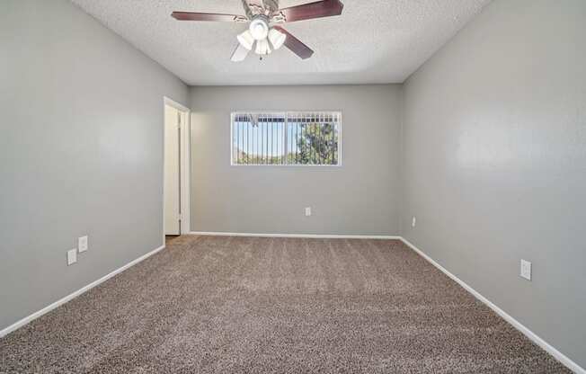 A room with a ceiling fan and carpeted floor.