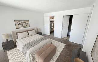 A bedroom with a large bed and a wardrobe in the background.