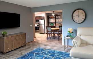 a living room with a large clock on the wall and a blue rug