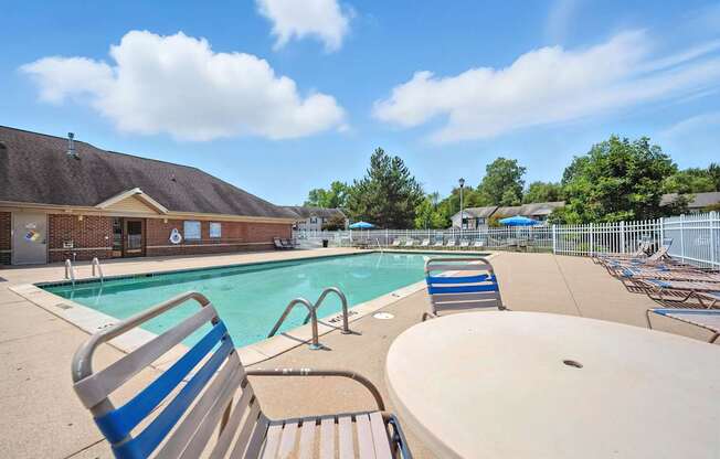 A sunny day at the pool with a blue sky and clouds at Arbors at Georgetown Apartments, Michigan, 48911