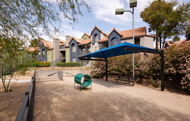 a park with a playground and a blue canopy