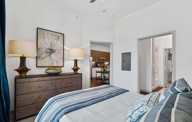 A bedroom with a bed, dresser, and two lamps.