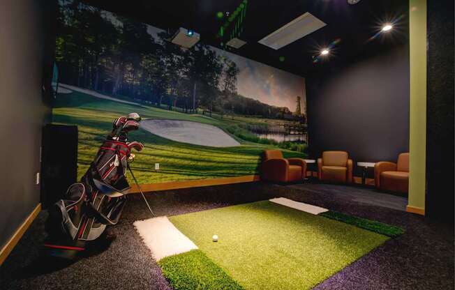 A room with a golf simulator and a green carpet.