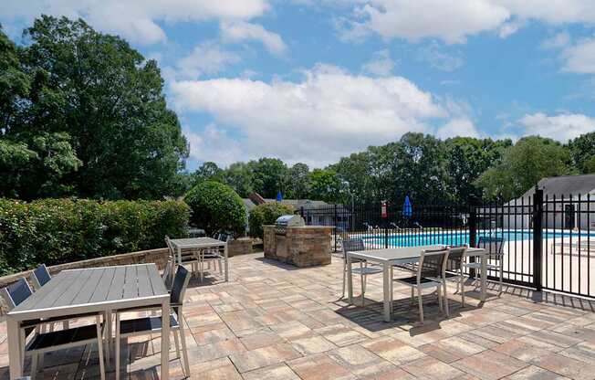 A pool surrounded by a black fence and a table with chairs.