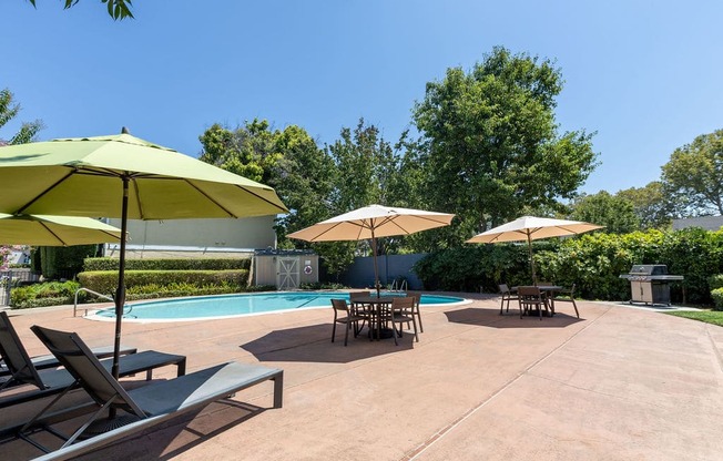 a swimming pool with patio furniture and umbrellas