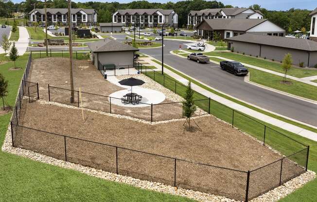 an aerial view of a fenced in park with a basketball court