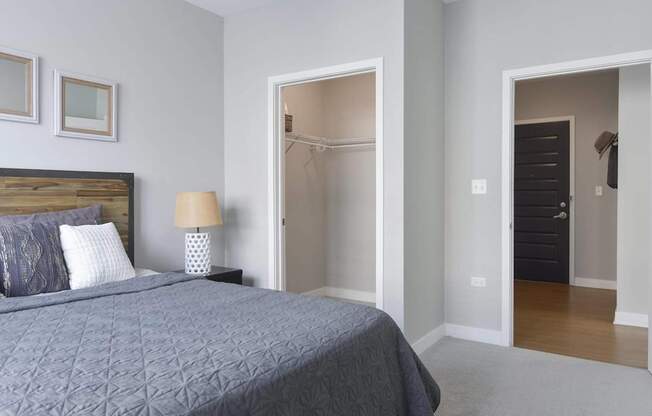 A bedroom with a bed, lamp, and two doors.