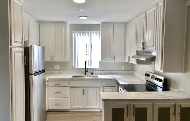 a kitchen with white cabinets and stainless steel appliances at The Flats on Addison, Sherman Oaks, 91423