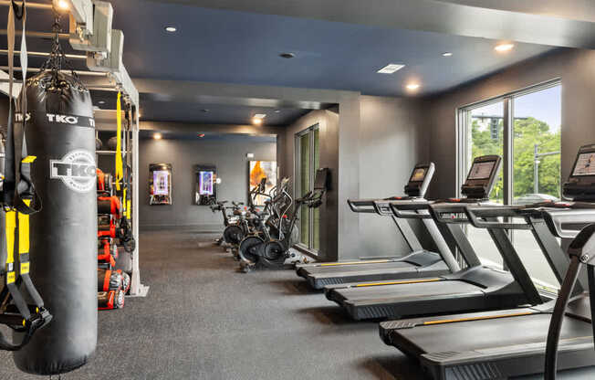 A gym with treadmills, exercise bikes, and a punching bag.