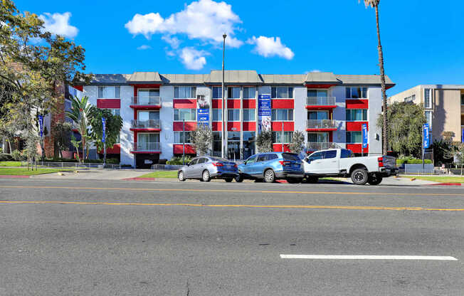 A hotel with red and white stripes and a parking lot in front.