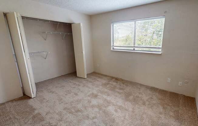 an empty room with a window and a closet