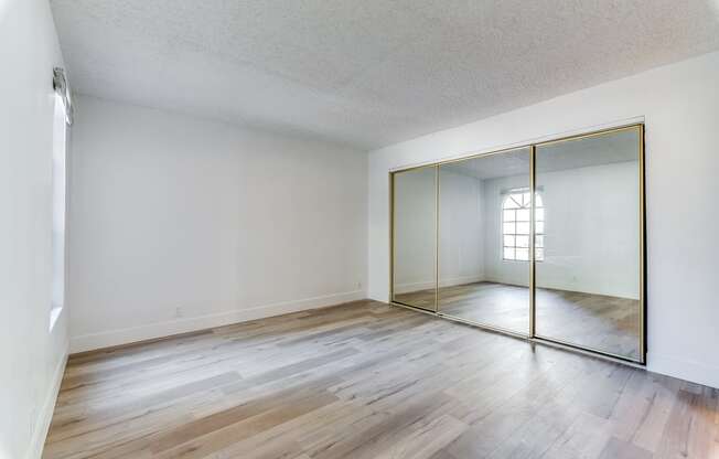 a bedroom with hardwood floors and a large mirror