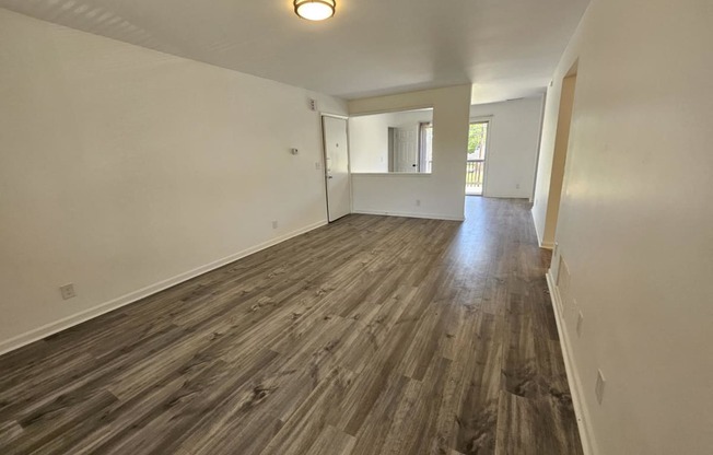 an empty living room with wood flooring and white walls