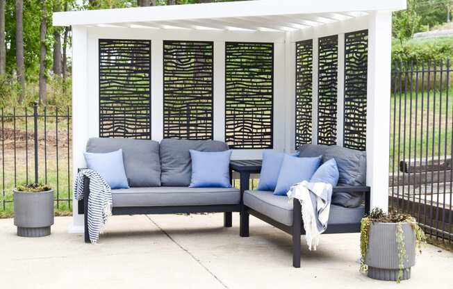 a covered patio with couches and pillows under a pergola