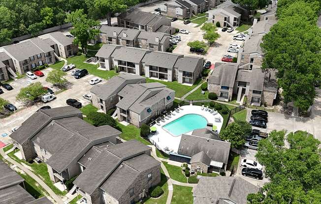 A bird's eye view of a residential area with houses and a swimming pool.