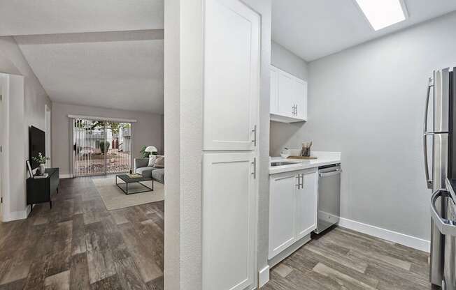 Model Kitchen with White Cabinets, Wood-Style Flooring and View of Living Room at Crystal Creek Apartments located in Phoenix, AZ.