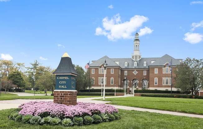 a brick building with a sign in front of a lawn with flowers