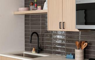 Streamlined cabinetry, open shelving, and a glossy tile backsplash bring warmth and texture to this thoughtfully designed kitchen.