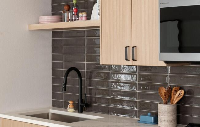 Streamlined cabinetry, open shelving, and a glossy tile backsplash bring warmth and texture to this thoughtfully designed kitchen.