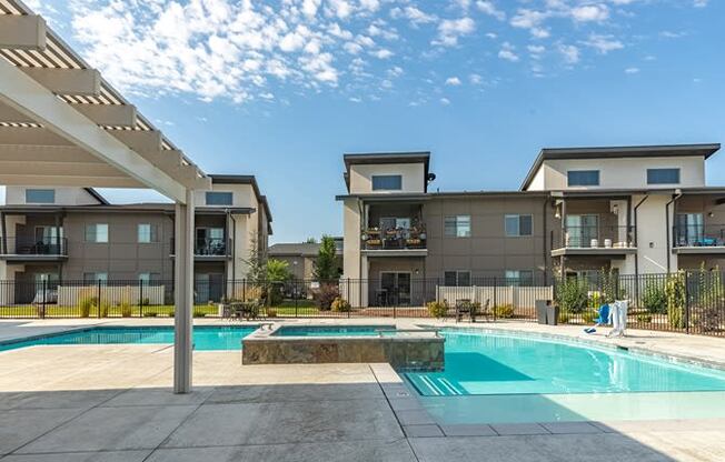 a swimming pool with a hot tub in front of an apartment building