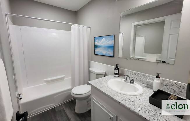 A bathroom with a white toilet, sink, and bathtub.